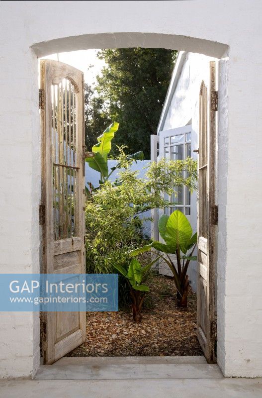 Antique wooden gates opening onto narrow boundary garden