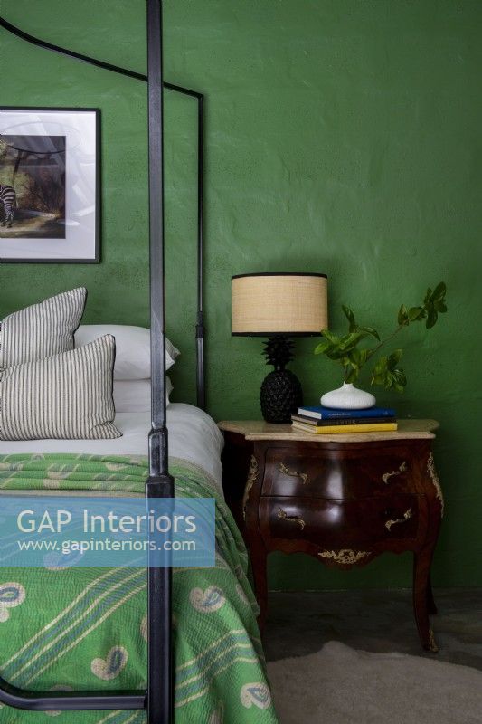Antique console table in bedroom with green feature wall