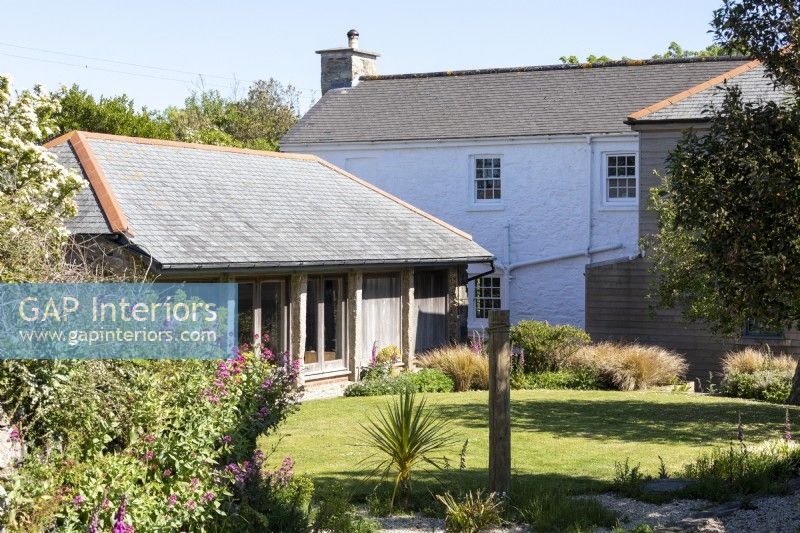 Sally and John Biddle's house in Cornwall, the exterior showing a lovely summer garden with stone barns and house