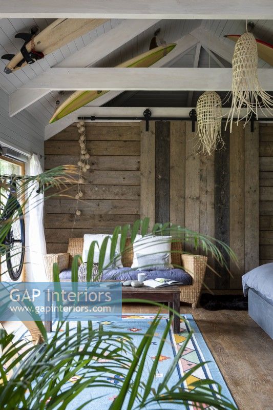 Converted barn with open beams and rustic wooden walls and surf boards as decoration 
