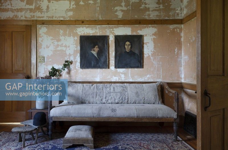 Vintage portrait paintings in rustic living room with distressed walls