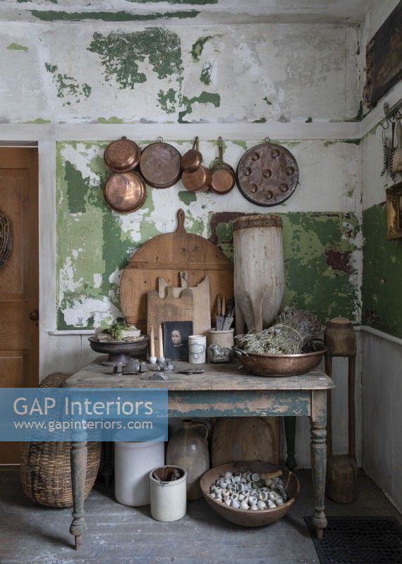 Copper pots and pans on distressed painted wall of rustic kitchen