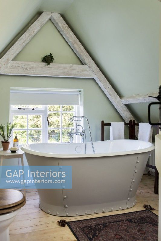 Studded freestanding bath by window in country bathroom