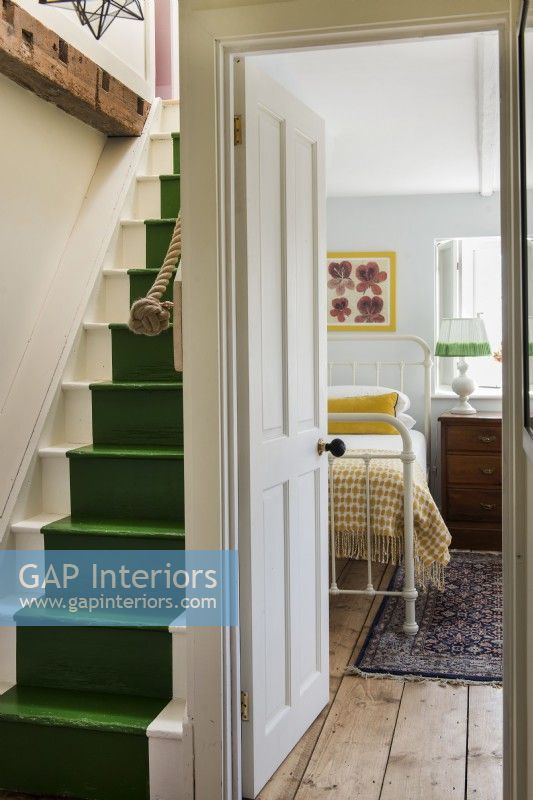 View into vintage style bedroom from landing with green painted stairs