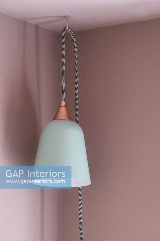 Detail of white lamp hanging against pink wall and ceiling 