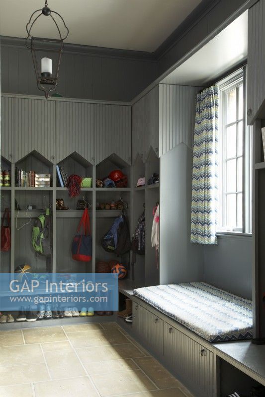 Gray painted mudroom with kids cubbies, seating area and storage