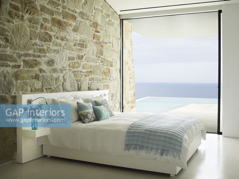 A guest room with ocean and pool views in a cliff side home on the Greek Island of Milos;