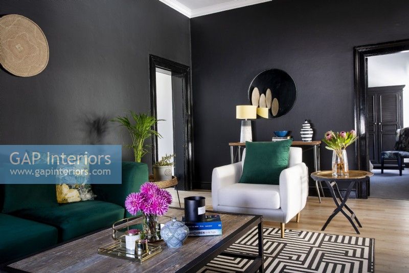 Living room with black walls, geometric rug and green sofa