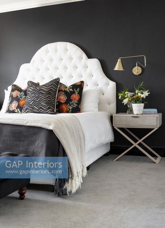 Bedroom with white deep buttoned headboard against black wall