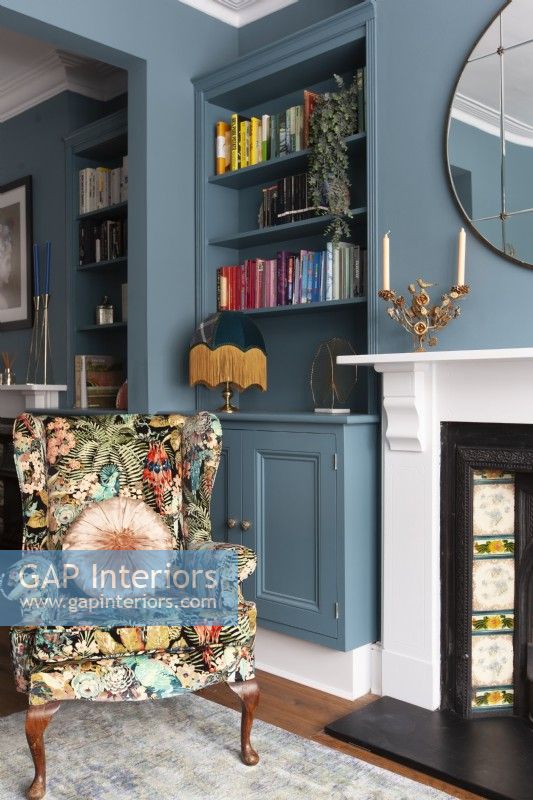Bold blue painted living room with botanical print armchair