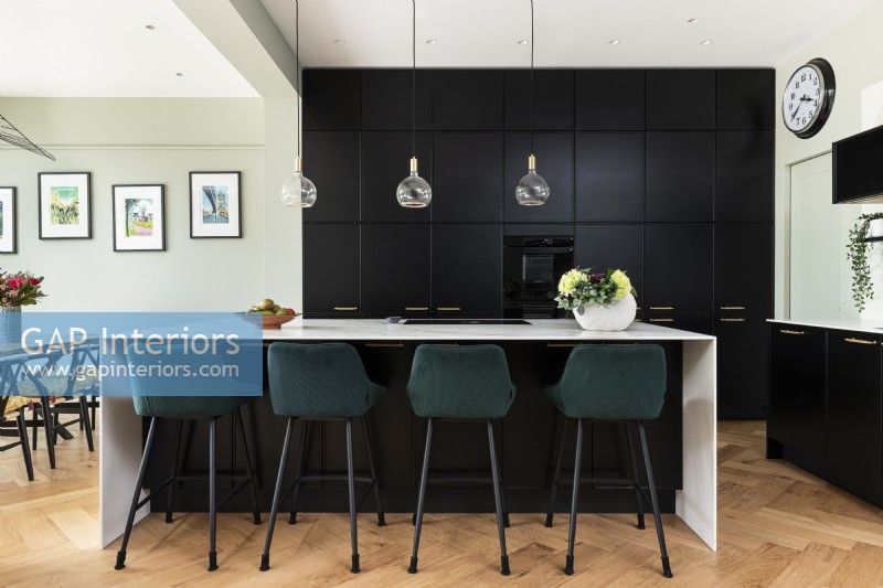 Contemporary kitchen with tall black wall units and island.