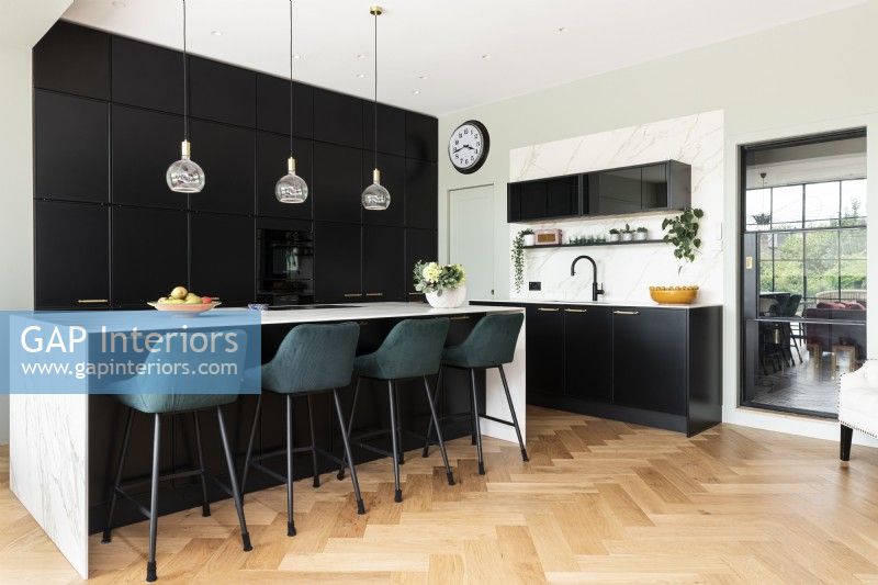 Contemporary large kitchen with tall black wall cupboards and island.