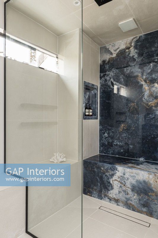 Wet room with large marble tiles and stepped glass screen.