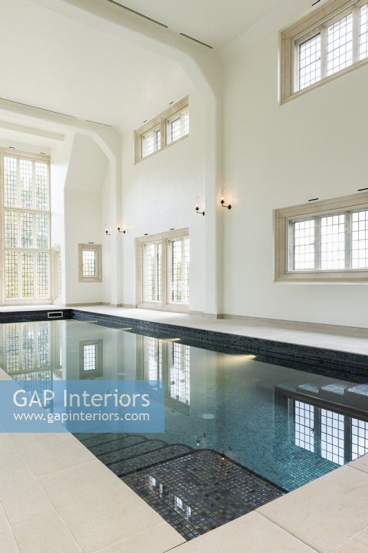 Large indoor swimming pool in a traditional building with floor to ceiling window. 