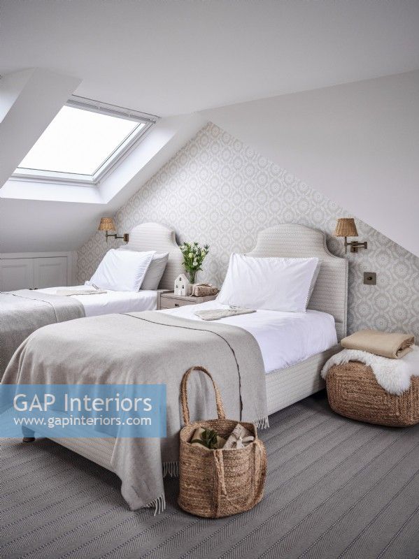 Neutral loft conversion bedroom with twin beds and skylight