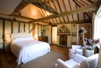 Boonshill Farm, East Sussex. Interior of bedroom with wooden floorboards and exposed beams. 