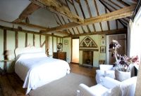 Boonshill Farm, East Sussex. Interior of bedroom with wooden floorboards and exposed beams. 