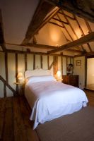 Boonshill Farm, East Sussex. Interior of bedroom with wooden floorboards and exposed beams 