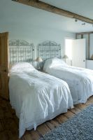 Boonshill Farm, East Sussex. Interior of guest bedroom with antique lace bedspreads and metal gates as bedheads. 