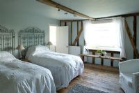 Boonshill Farm, East Sussex. Interior of guest bedroom with antique lace bedspreads and metal gates as bedheads. 