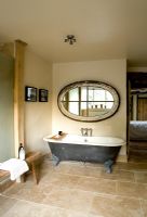 Boonshill Farm, East Sussex. Interior of bathroom with roll top bath, wooden bench from india  and mirror made from old window.