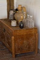Boonshill Farm, East Sussex. Antique Chinese chest stands on original brick floor with Spanish pot and antique Indian carved stone head. 