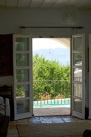 Corfu, Greece. Yialiskari House Villa near Kalami. View through living room to pool and Albanian Mountains