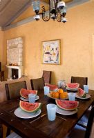 Corfu, Greece. Malama House near Barbati. Dining room with table and chairs set for dining. water melons on table