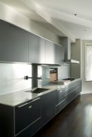 Contemporary kitchen with black units and composite worktop