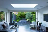 Interior of living area leading out onto patio and contemporary garden designed by Charlotte Rowe