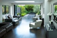 Interior of pen plan  living and dining area leading out onto patio and contemporary garden designed by Charlotte Rowe