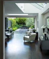 Interior of open plan  living and dining area leading out onto patio and contemporary garden designed by Charlotte Rowe