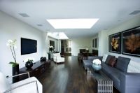Interior of open plan  living and dining area with skylight, wooden floor and contemporary furniture