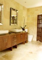 Classic bathroom with twin basins and dark wood cupboards  Large sandstone tiles and wooden screen