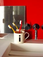 Detail of modern bathroom sink with mug holding toothbrushes
