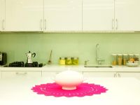 Modern kitchen with teapot on pink table mat