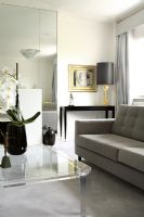 Grey sofa in classic living room with console tale in background and glass coffee table