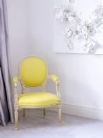 Living room with classic upholstered yellow chair and abstract art on the wall
