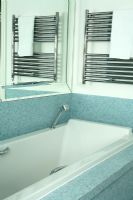 Modern bath with blue mosaic tiles and towel hanging on towel radiator