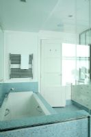 Modern bathroom with blue mosaic tiles and hand held shower on bath