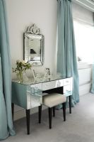 Classic bedroom with mirrored dressing table and ornate mirror and duck egg blue curtains