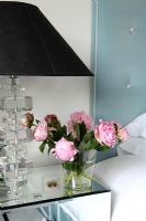 Detail of roses and lamp on mirrored bedside cabinet