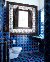 Quirky bathroom with blue tiles and large ornate cabinet 