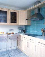 Modern kitchen with breakfast bar, light wood units and green tiled splashback