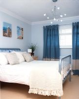 Modern bedroom with double bed, chandelier and blue curtains