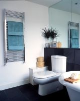 Modern bathroom with toilet, towel radiator and black slate wall and floor tiles