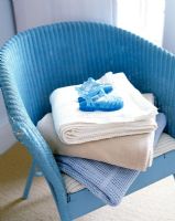 Detail of blue chair with folded blankets and childs shoes 