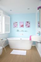 Modern bathroom with blue painted walls, freestanding bath and wooden floor