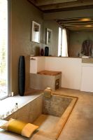 Rustic bathroom with concrete walls and floor and sunken bath 