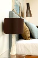 Detail of modern bedroom with cushions on bed and side table with lamp